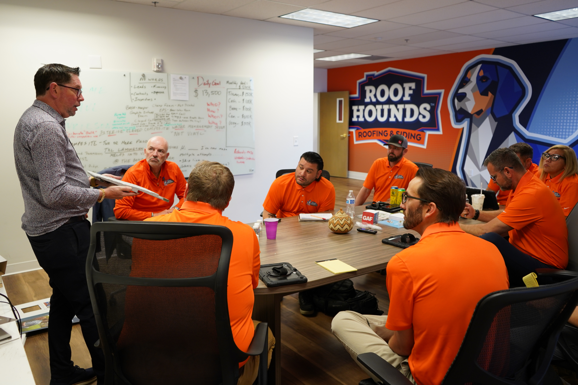 Roof Hounds team in their office in salt lake county discussing ways to help customers with roofing services